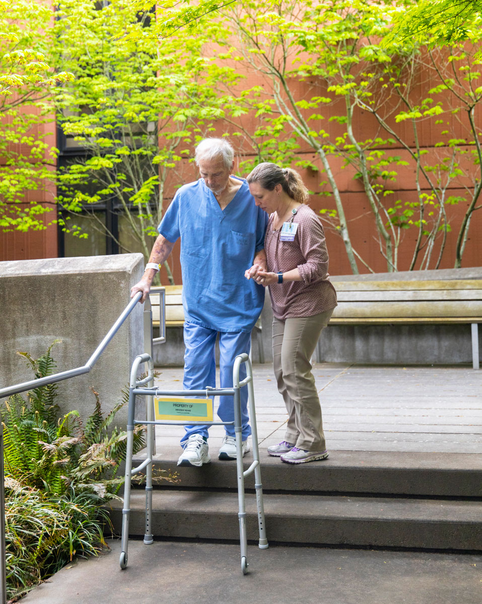 Patient and rehab specialist practicing in the Salem Health therapy courtyard.