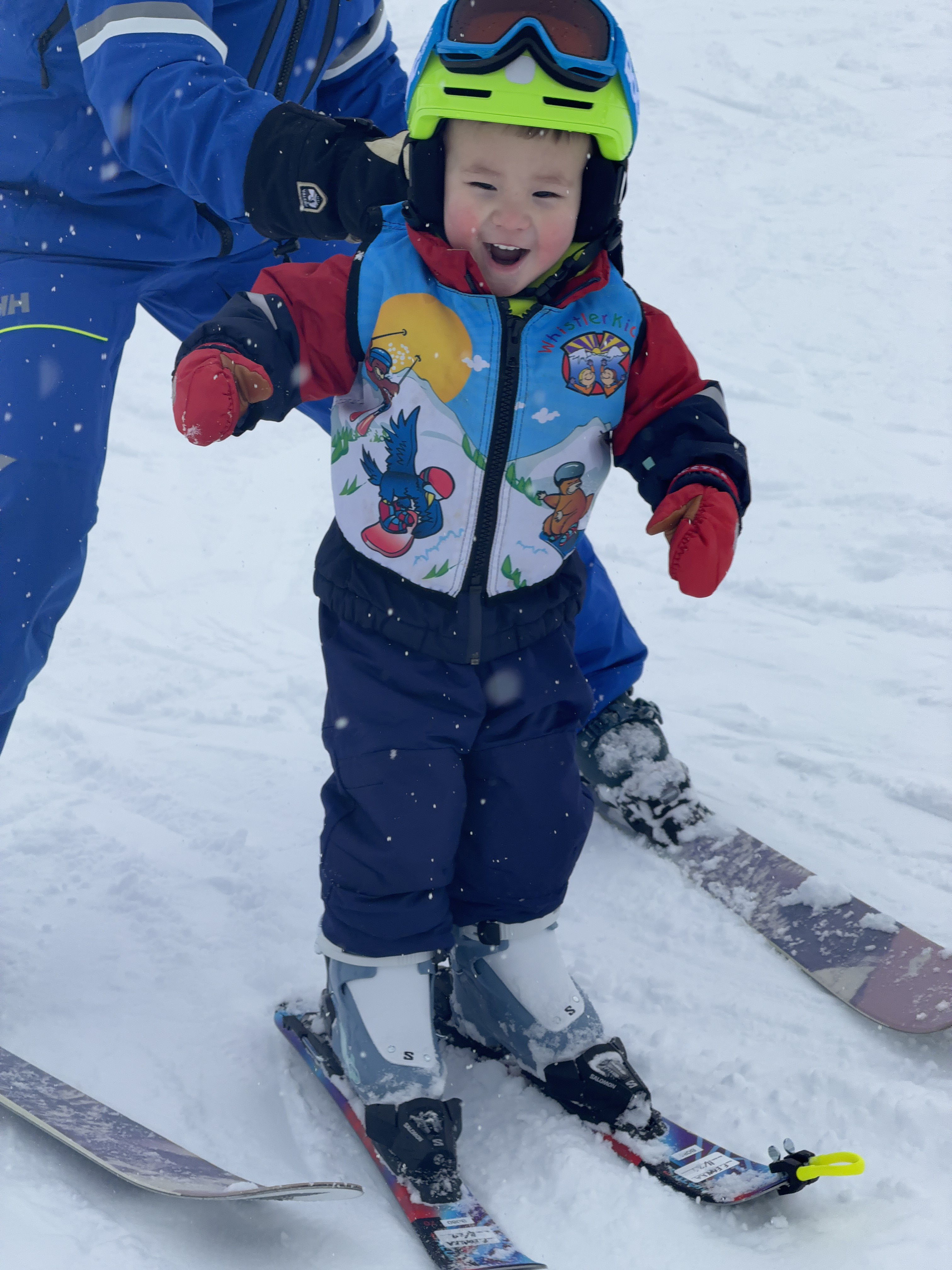 A small boy smiles on skis in the snow.