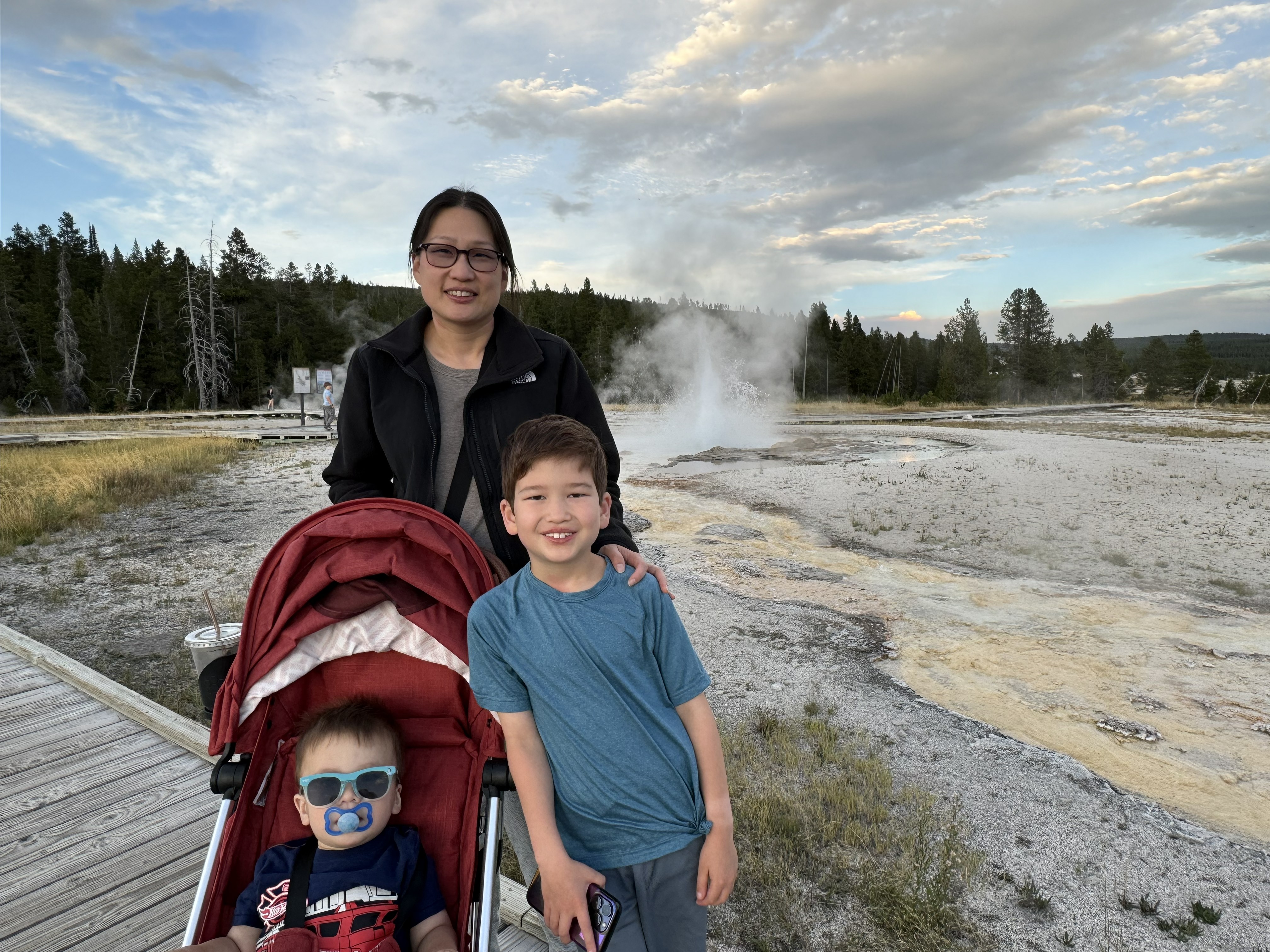 A woman and two young boys pose in front of the bubbling mud pots in Yellowstone National Park.