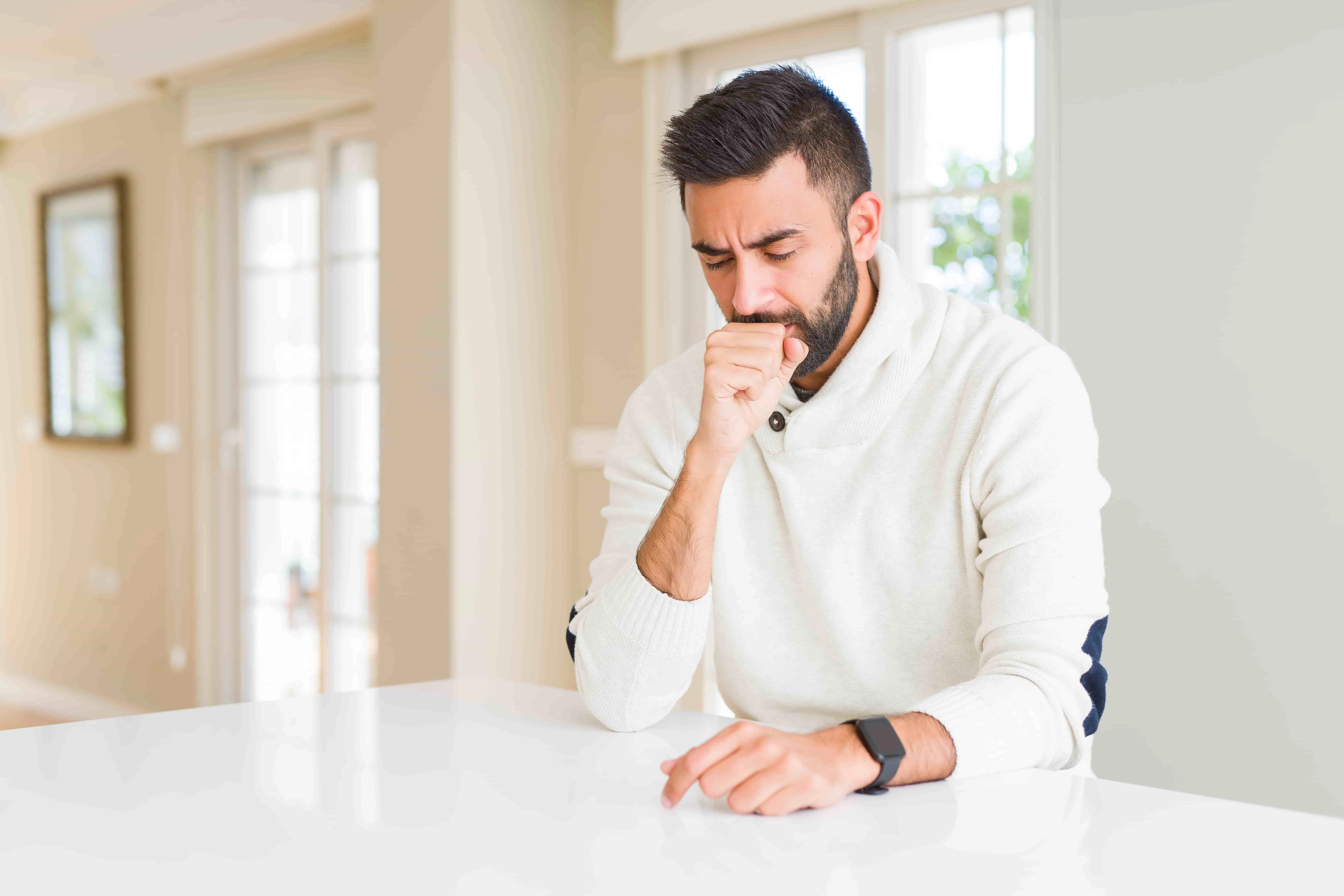 man with asthma coughing while at home.