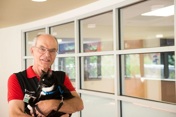 George holding his black and white therapy cat, Junior.