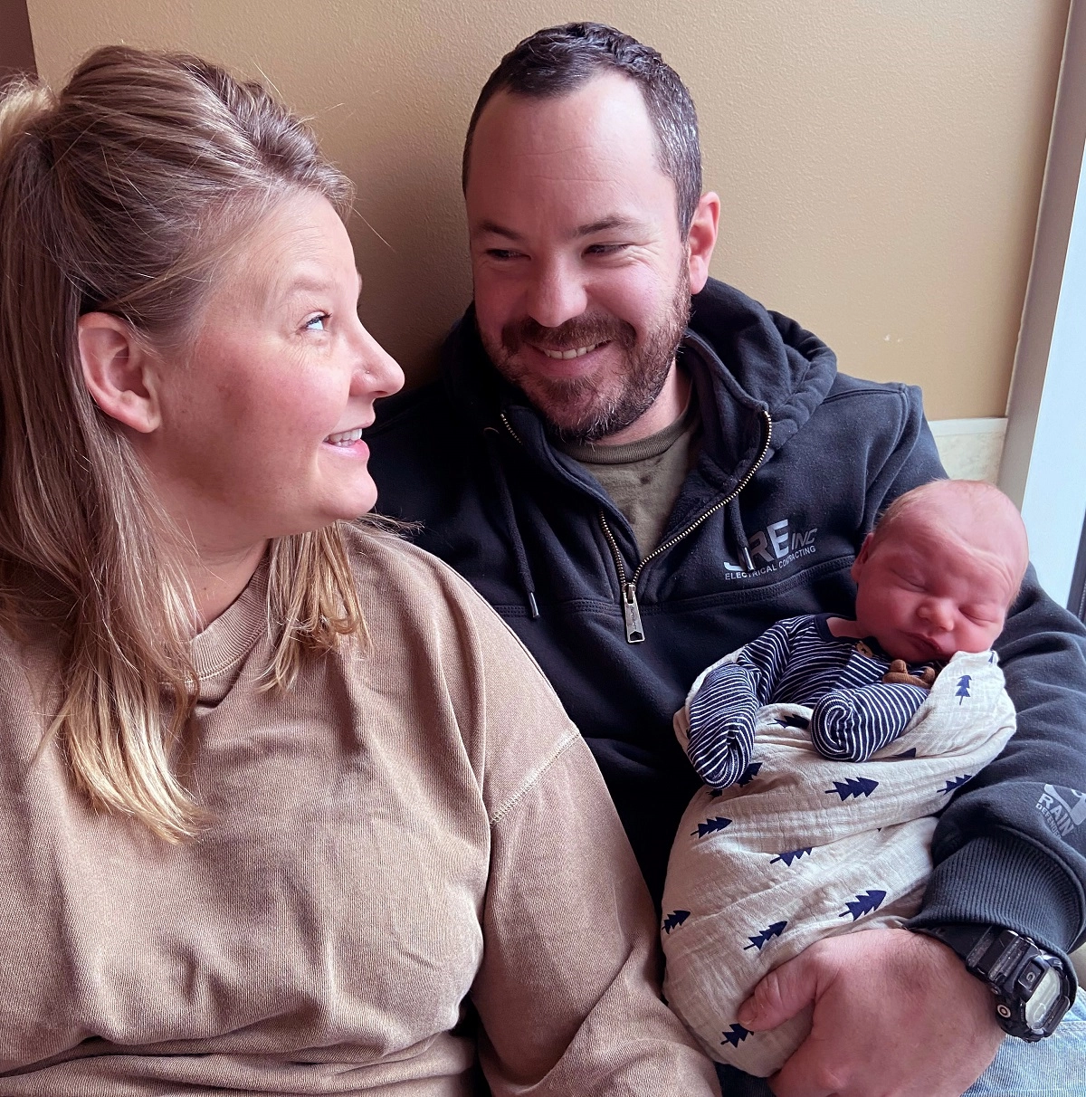 Parents of 2022 first baby smiling at each other as the mother holds the newborn.