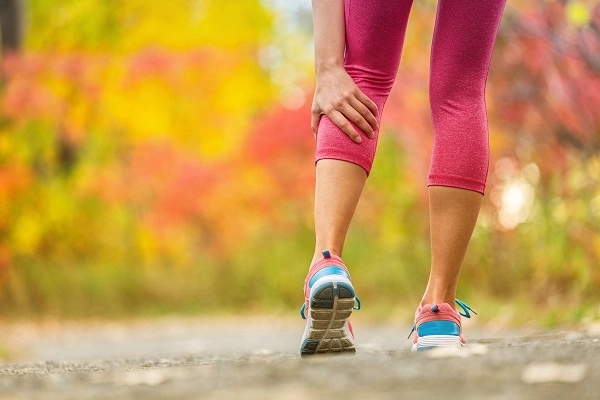 Woman in pink leggings has a calf cramp.