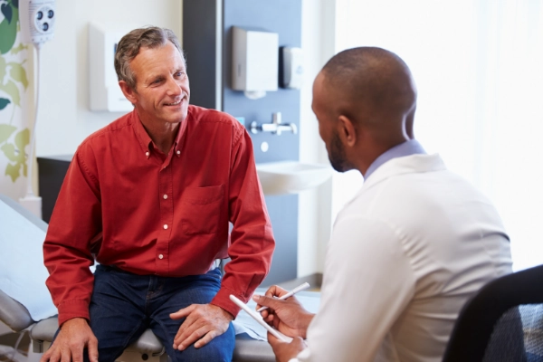 Senior man talking with doctor in an exam room.