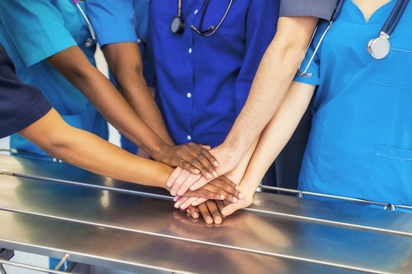 Nurses with hands stacked on each other in a huddle.