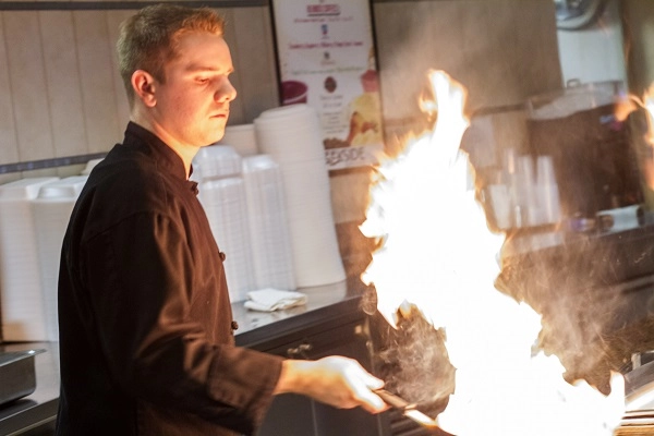 Chef prepares flame-cooked veggies.