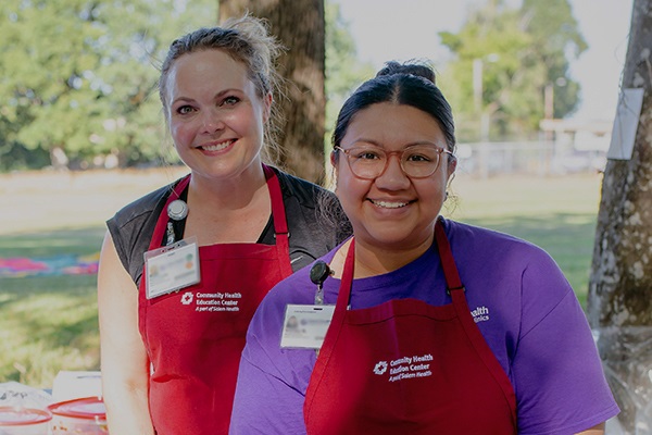 Two Salem Health CHEC staffers smiling at community event.