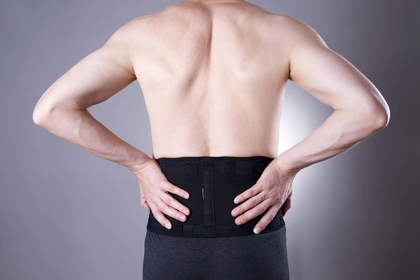 A man supporting his back with both of his hands.