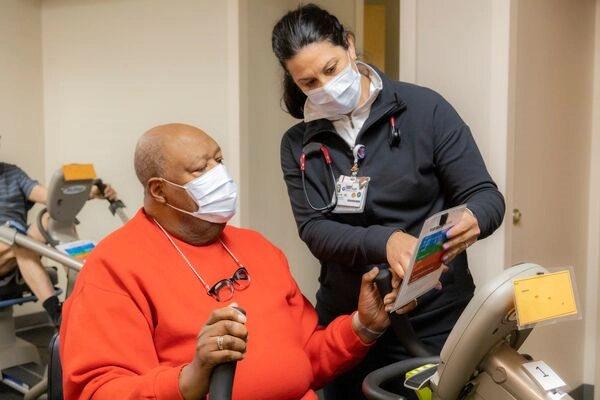 Cardiac rehab therapist showing a patient proper exercise technique