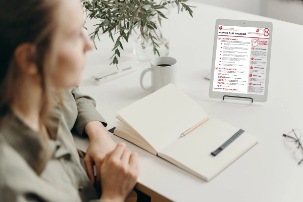 A woman sitting at a desk reading a document on a tablet