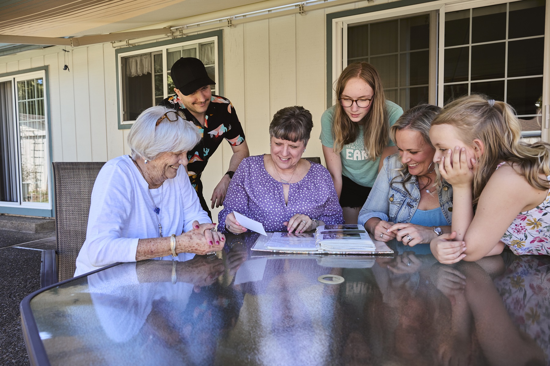 Brenda and her family gathered around a patio table looking at photo albums.