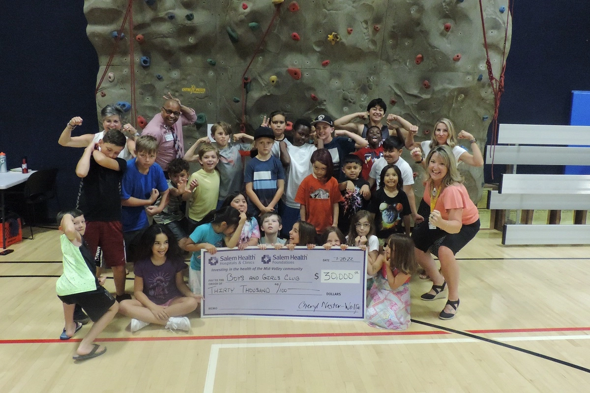 Community Relations giant check presentation to Boys and Girls Club 2022 - kids in front of rock climbing wall
