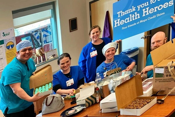A group of emergency room staff pose with boxes of mini cupcakes donated by Maps Credit Union.