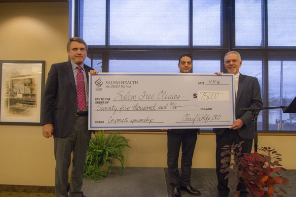 Check presentation by Salem Health representatives — Bob Wells (left), chair of Salem Health Board of Trustees, and Bahaa Wanly (center), VP of Salem Health Medical Group and interim CIO — to John McConville (right), CEO of Salem Free Clinics.