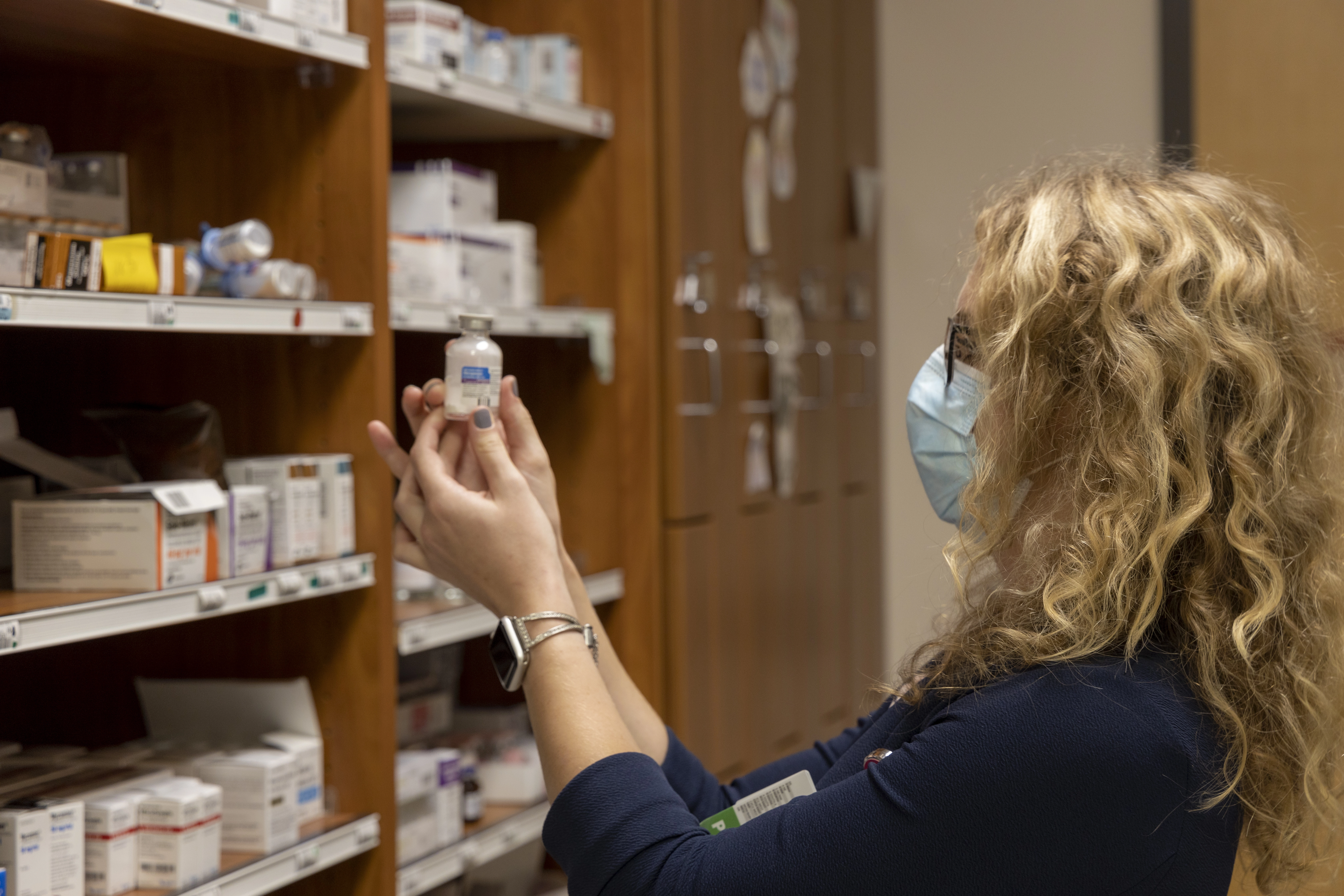 Pharmacy resident pictured with shelves of medication.