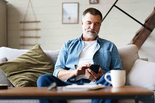 Male college student using smartphone in his dorm