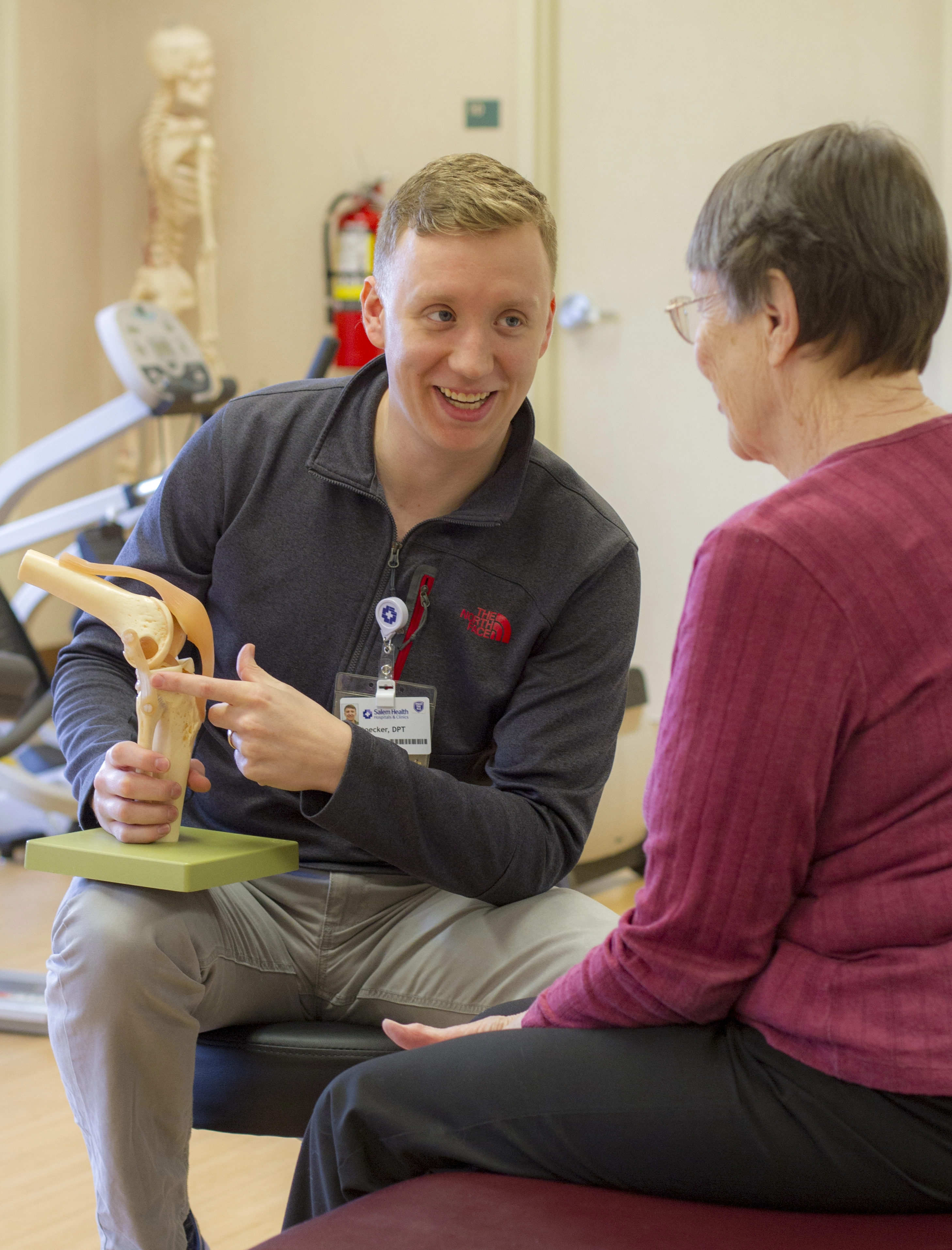 A PT shows a patient a 3-D model of the anatomical structures of the knee.