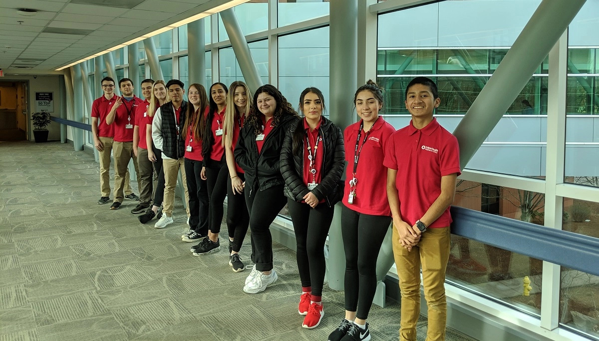 HS volunteers skybridge cropped A group of high school volunteers in red polo shirts line up in the Salem Hospital skybridge.