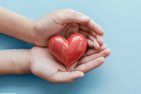 Two hands holding a ceramic heart.