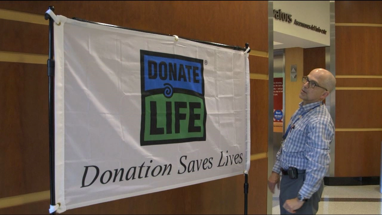 man adjusts Donate Life, organ donation flag in the lobby of Building A