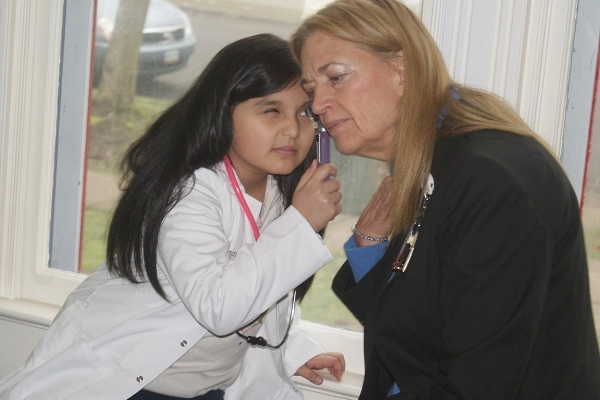 A child pretends to check Salem Health CEO's ears with a toy otoscope