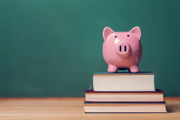 A piggybank on top of a stack of books.