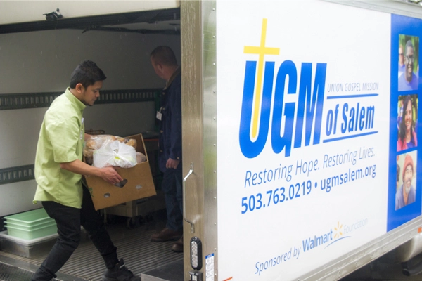 Workers carry boxes of donated goods into the UGM donation box truck